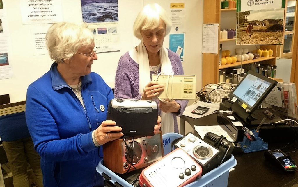 Oddveig Øygard og Anne Marie Stoknes til høgre med en av kassene med radioer de har fått inn til NMS Gjenbruk i Ålesund.