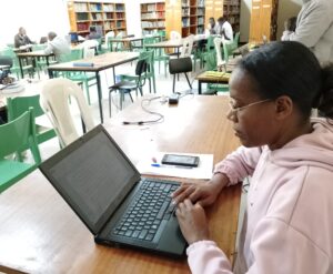 Bildet viser Azalech i lesesalen foran laptopen sin