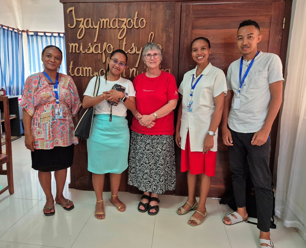 Bildet viser fem personer foran mottoet av sykehuset